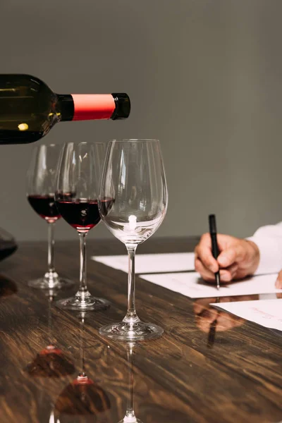 Vue partielle du sommelier écrivant à table avec des verres à vin — Photo de stock
