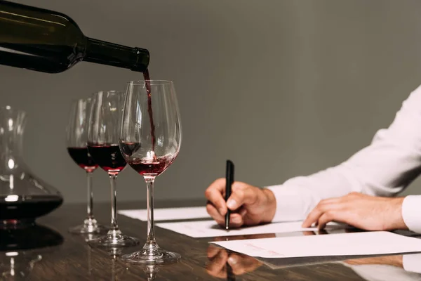 Частковий вид на сомельє, що пише за столом з келихами для вина — стокове фото