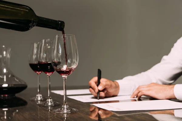 Vista parcial de la escritura sommelier en la mesa con copas de vino - foto de stock