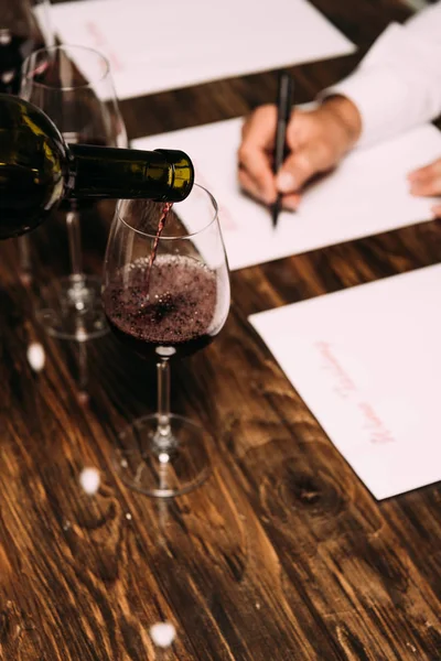 Vue partielle du sommelier écrivant à table avec des verres à vin — Photo de stock