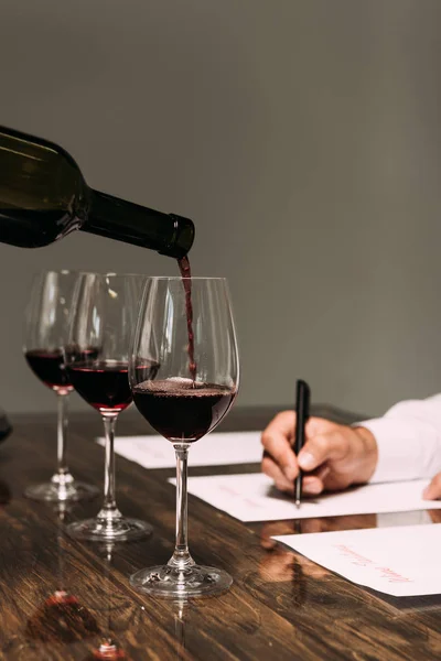 Vue partielle du sommelier écrivant à table avec des verres à vin — Photo de stock