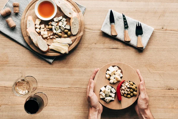 Cropped view of sommelier at table with wine glasses, food and cutlery — Stock Photo