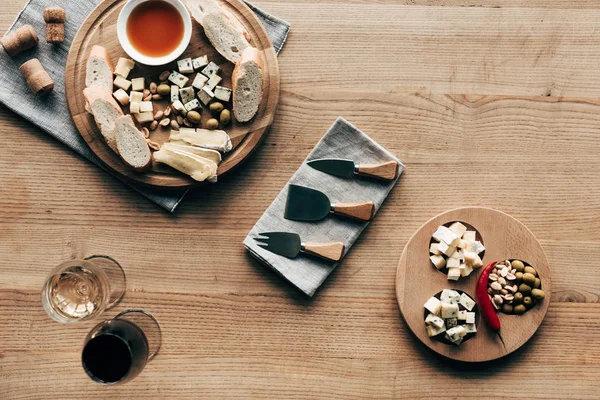 Вид зверху на келихи для вина, соус, хліб, сир, оливки, пробки та посуд на дерев'яній поверхні — стокове фото