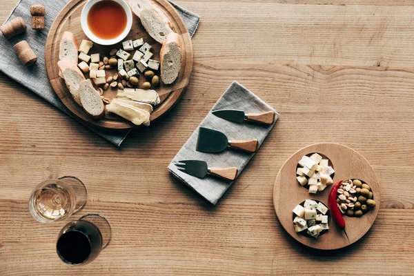 Top view of wine glasses, sauce, bread, cheese, olives, corks and cooking utensils on wooden surface — Stock Photo