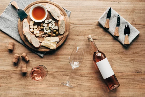 Top view of wine glasses, bottle of wine, sauce, bread, cheese, olives, corks and cooking utensils on wooden surface — Stock Photo