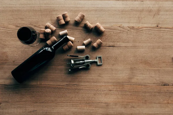 Draufsicht auf Flasche Wein, Weinglas, Korken und Korkenzieher auf Holzoberfläche — Stockfoto