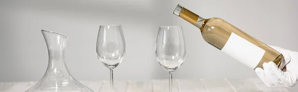 Panoramic shot of waiter in white glove pouring wine in wine glasses — Stock Photo