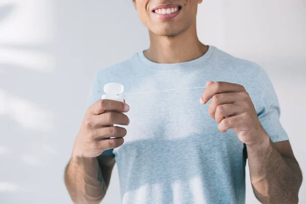 Cropped view of man holding dental floss while standing in sunlight — Stock Photo
