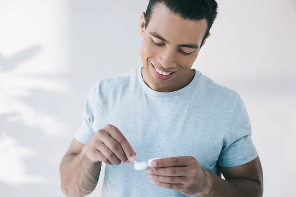 Junger Mann hält Behälter für Linse und versucht Kontaktlinse zu nehmen — Stockfoto