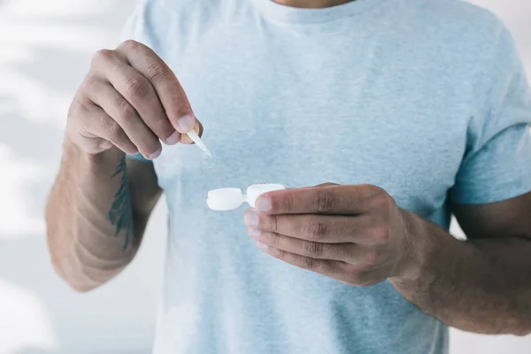 Vue recadrée de l'homme prenant une lentille de contact avec une pince à épiler du contenant — Photo de stock