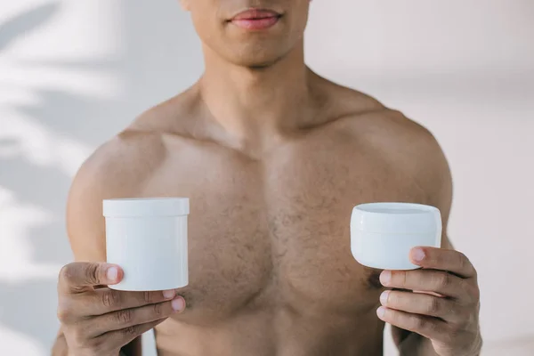 Cropped view of muscular mixed race man holding two containers — Stock Photo
