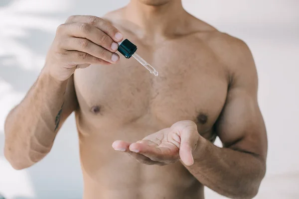 Cropped view of man dropping serum from pipette on hand — Stock Photo