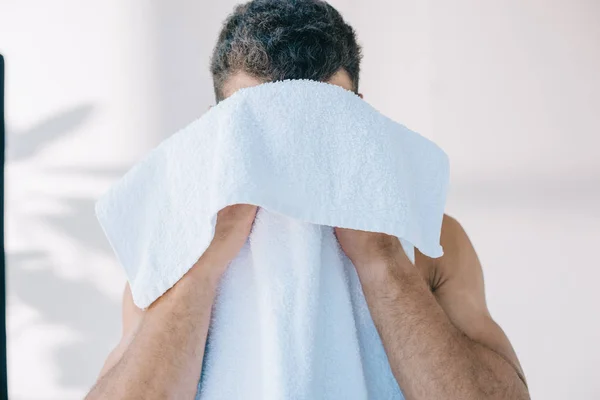 Jovem muscular limpando rosto com toalha azul — Fotografia de Stock