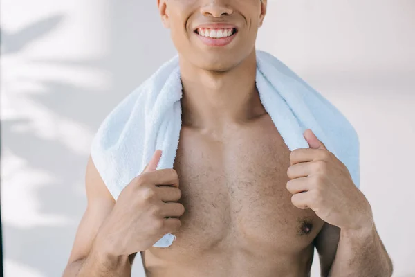 Cropped view of muscular mixed race man holding blue towel on shoulders — Stock Photo