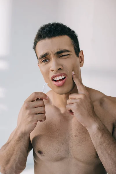 Homem bonito com dor de dente segurando fio dental no pau e olhando para longe — Fotografia de Stock