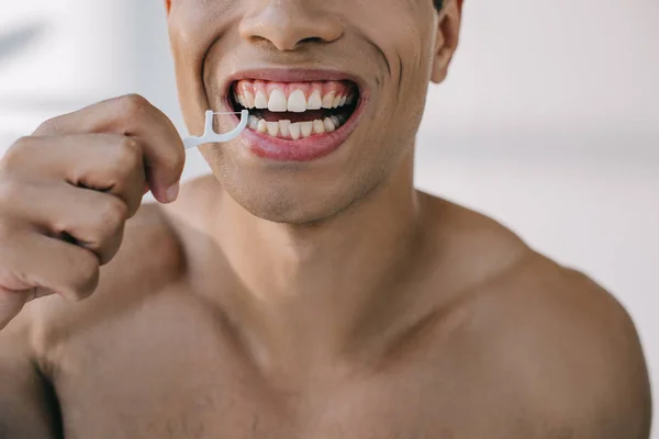 Cropped view of mixed race man using dental floss on stick — Stock Photo