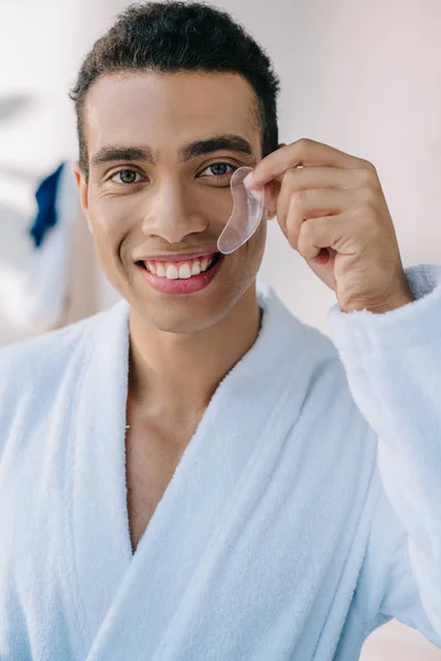 Handsome young man in bathrobe showing patch and smiling while looking at camera — Stock Photo