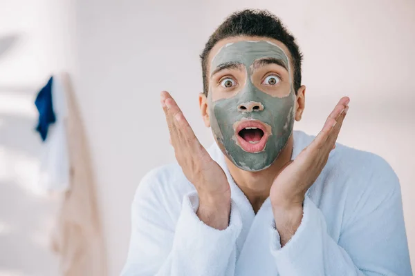 Uomo scioccato con maschera di argilla sul viso gesticolando guardando la fotocamera — Foto stock