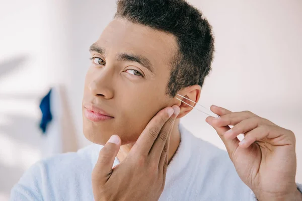 Handsome man plucking temple with tweezer and looking at camera — Stock Photo