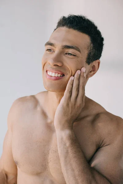 Handsome muscular man touching face with hand and looking away — Stock Photo