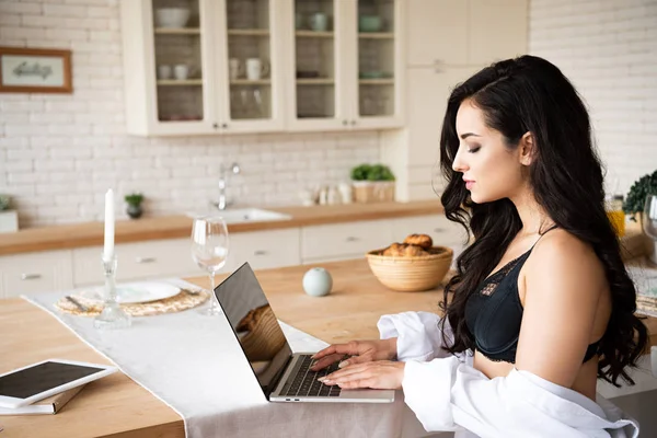 Side view of sexy girl in black underwear and white shirt using laptop — Stock Photo