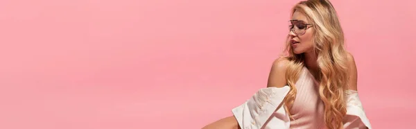 Plano panorámico de hermosa chica rubia en traje de cuerpo y gafas de sol posando en rosa - foto de stock
