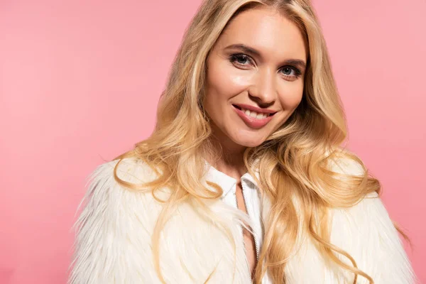 Mujer rubia hermosa feliz en chaqueta de piel sintética blanca aislada en rosa - foto de stock