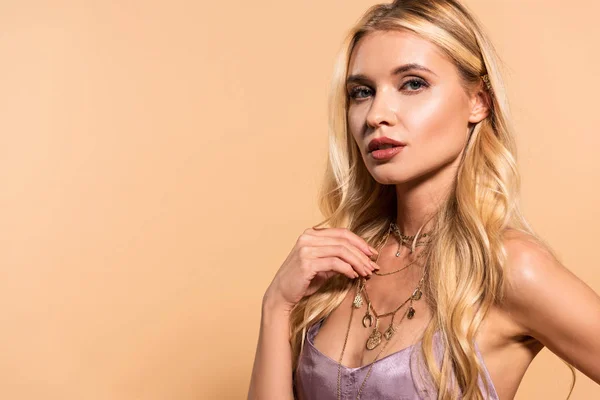 Elegante blonde Frau in violettem Satinkleid, die Halskette in Beige berührt — Stockfoto