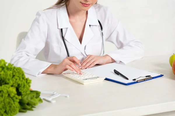 Cropped view of dietitian using calculator at workplace — Stock Photo
