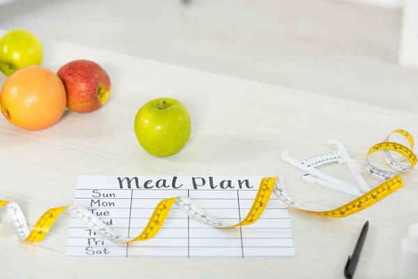Meal plan, measure tape, caliper, pen and fresh fruits on wooden surface — Stock Photo