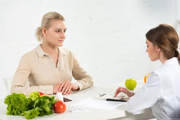 Dietitian and patient at table with fresh food — Stock Photo