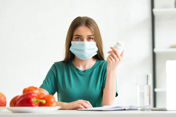 Front view of woman in medical mask holding pills — Stock Photo