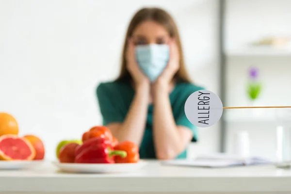 Selective focus of woman in medical mask propping face with hands and nameplate with inscription allergy — Stock Photo