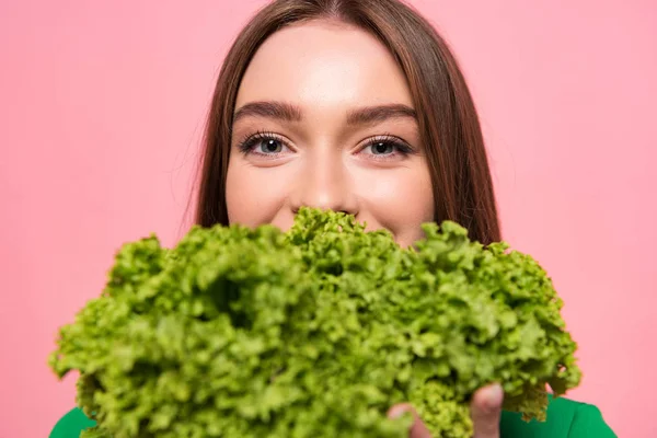 Vorderansicht der attraktiven jungen Frau mit Salat und Blick auf die Kamera isoliert auf rosa — Stockfoto