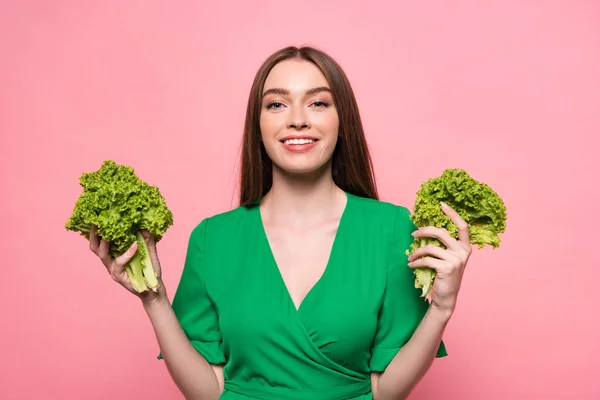 Vorderansicht der attraktiven jungen Frau mit Salat und Blick auf die Kamera isoliert auf rosa — Stockfoto