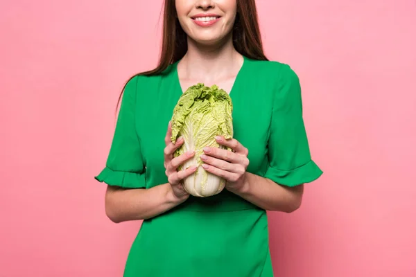 Cropped view of smiling girl holding chinese cabbage on pink — Stock Photo