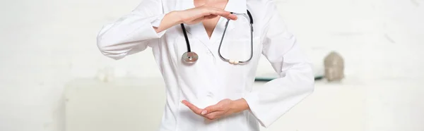 Panoramic shot of doctor in white coat with stethoscope gesturing in clinic — Stock Photo