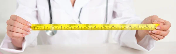 Panoramic shot of dietitian in white coat with stethoscope holding measure tape — Stock Photo