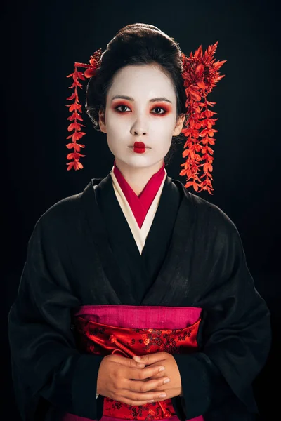 Bela gueixa em kimono preto e vermelho e flores no cabelo isolado em preto — Fotografia de Stock