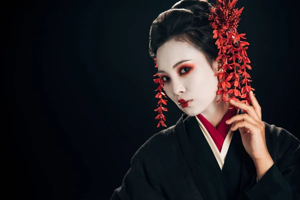 Hermosa geisha en kimono negro y rojo y flores en pelo aislado en negro con espacio de copia - foto de stock