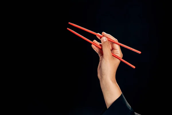 Vue recadrée de femme tenant des baguettes isolées sur noir — Photo de stock