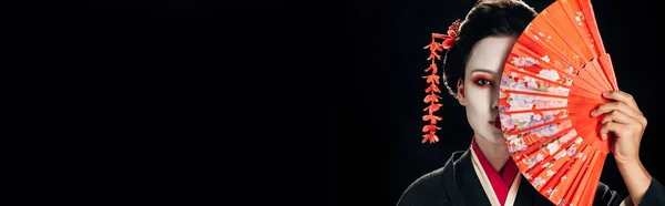 Gueixa atraente em quimono preto com flores no cabelo segurando ventilador mão brilhante isolado em preto, tiro panorâmico — Fotografia de Stock