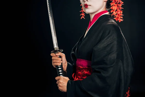 Vista parziale di bella geisha in kimono nero tenuta katana isolata su nero — Foto stock
