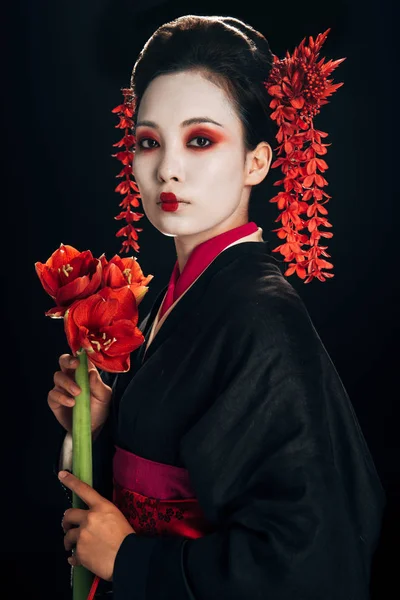 Schöne Geisha im schwarzen Kimono mit roten Blüten isoliert auf schwarz — Stockfoto