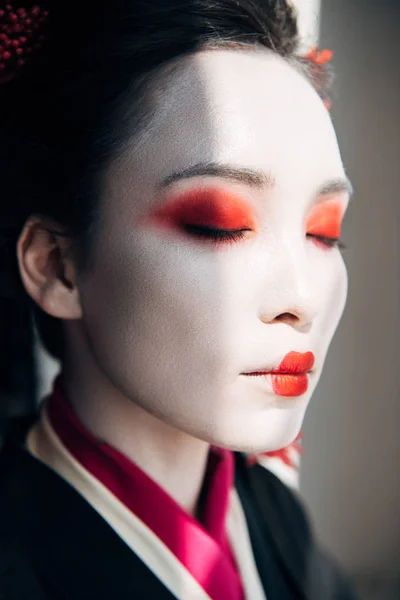 Портрет красивої гейші з червоно-білим макіяжем із закритими очима на сонячному світлі — стокове фото