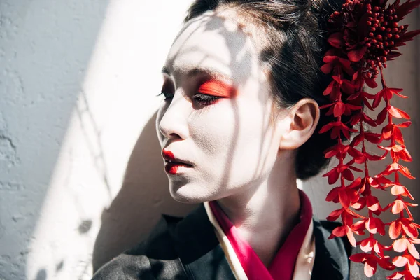 Portrait of beautiful geisha with red and white makeup in sunlight with shadows — Stock Photo