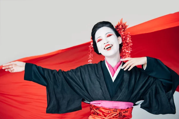 Счастливая красивая гейша в черном кимоно с красной тканью на фоне изолированы на белом — стоковое фото