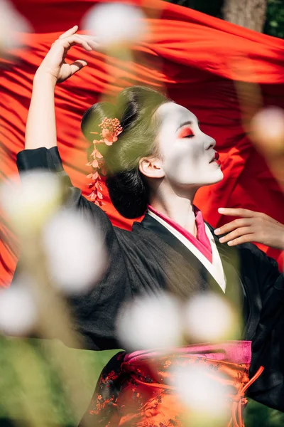 Selektiver Fokus von Ästen und schönen Geisha-Tänzen mit rotem Tuch auf dem Hintergrund im Sonnenlicht — Stockfoto