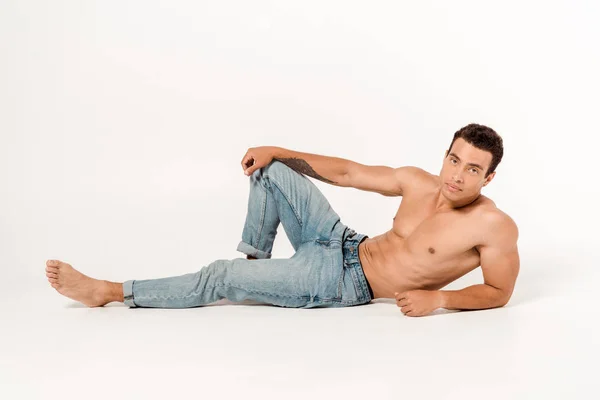 Schöner hemdloser Mann in blauer Jeans auf weißem Grund — Stockfoto