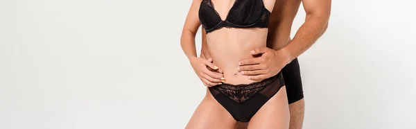 Panoramic shot of man touching sexy woman in black underwear isolated on white — Stock Photo